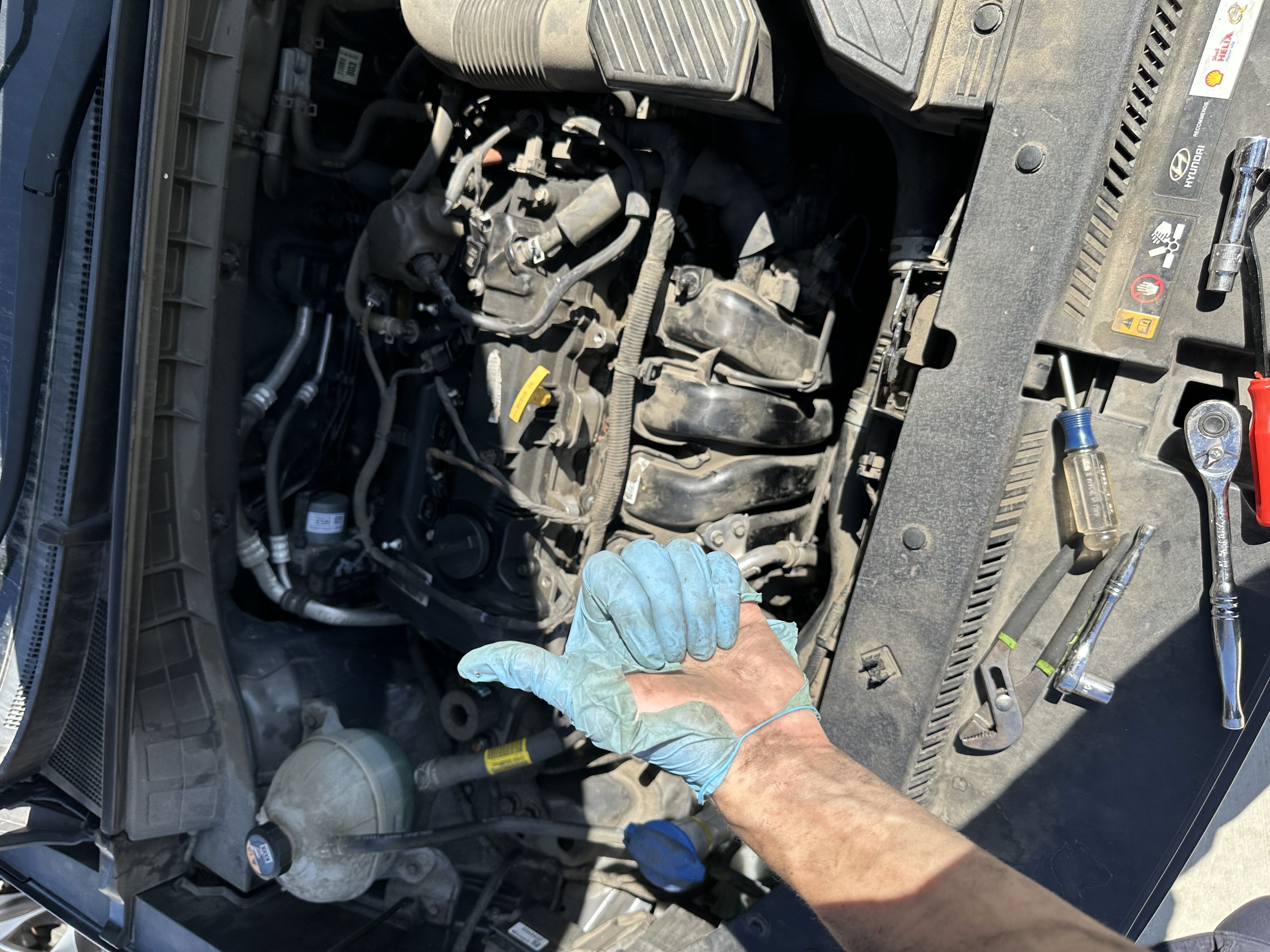 Coastline Auto mobile mechanic giving a thumbs up over a Hyundai engine bay during a driveway service call in the Inland Empire